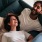 a couple laughing on a couch indoors